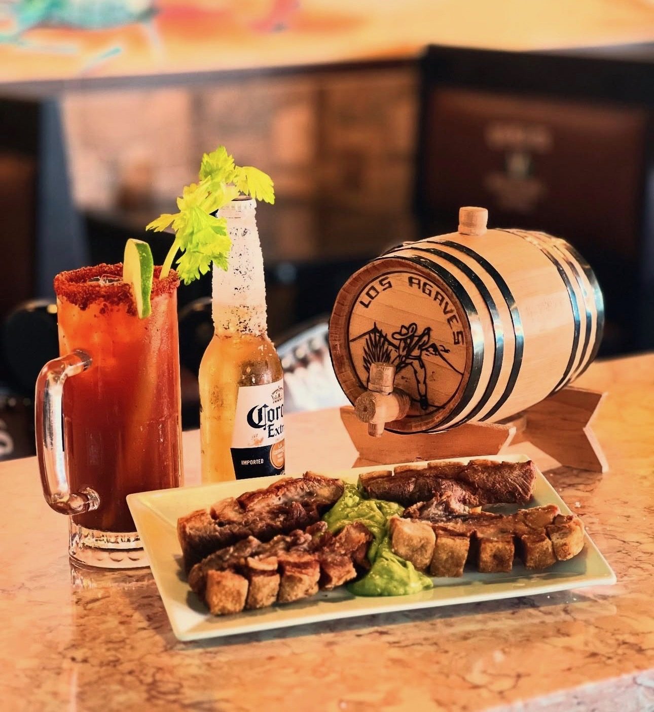 Chicharron with guacamole, a michelada and an ice-cold beer next to the Los Agaves barrel